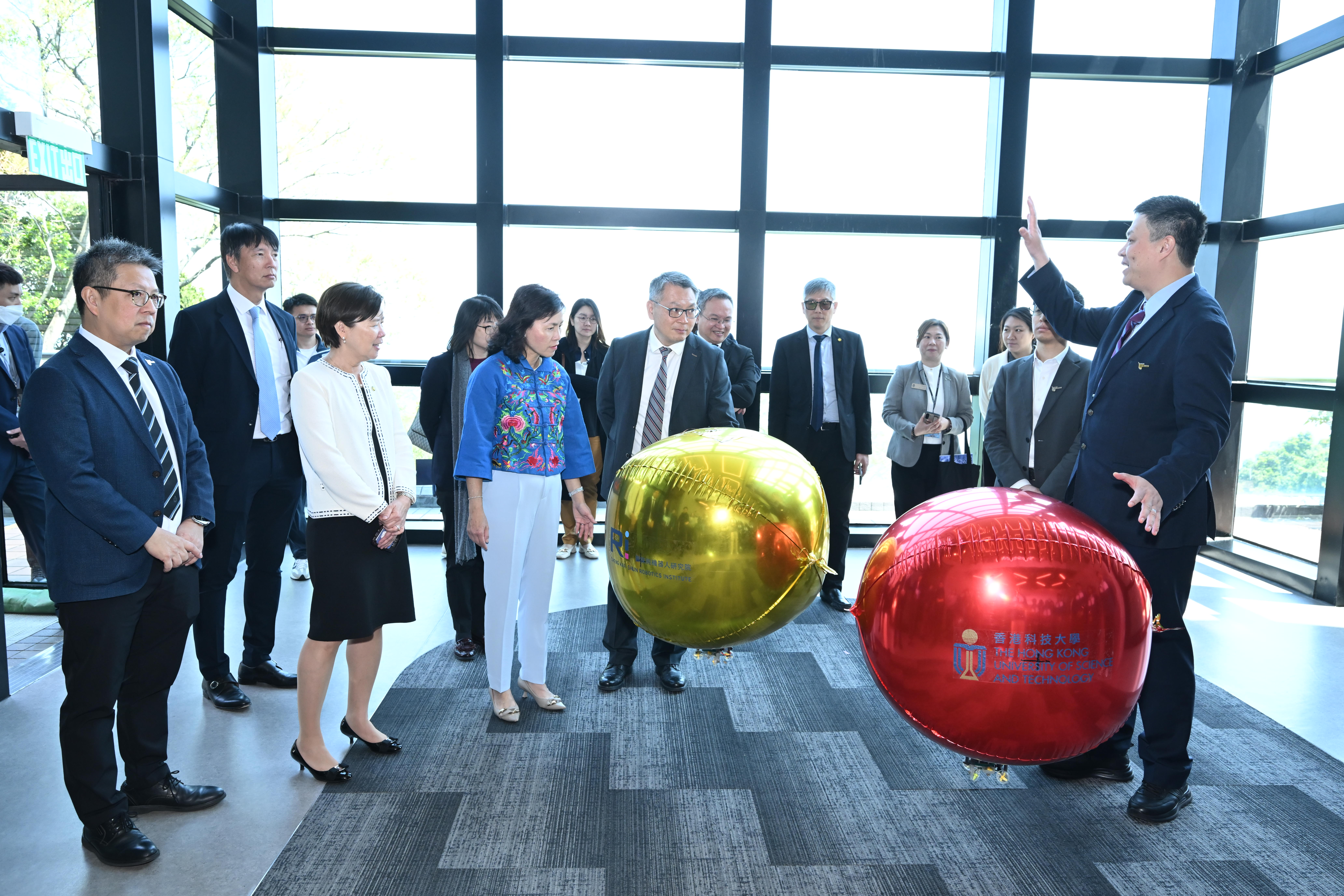 科大郑家纯机器人研究院院长张福民教授（前排右一），向嘉宾示范这款可近距离安全接近公众的微型自主飞艇。