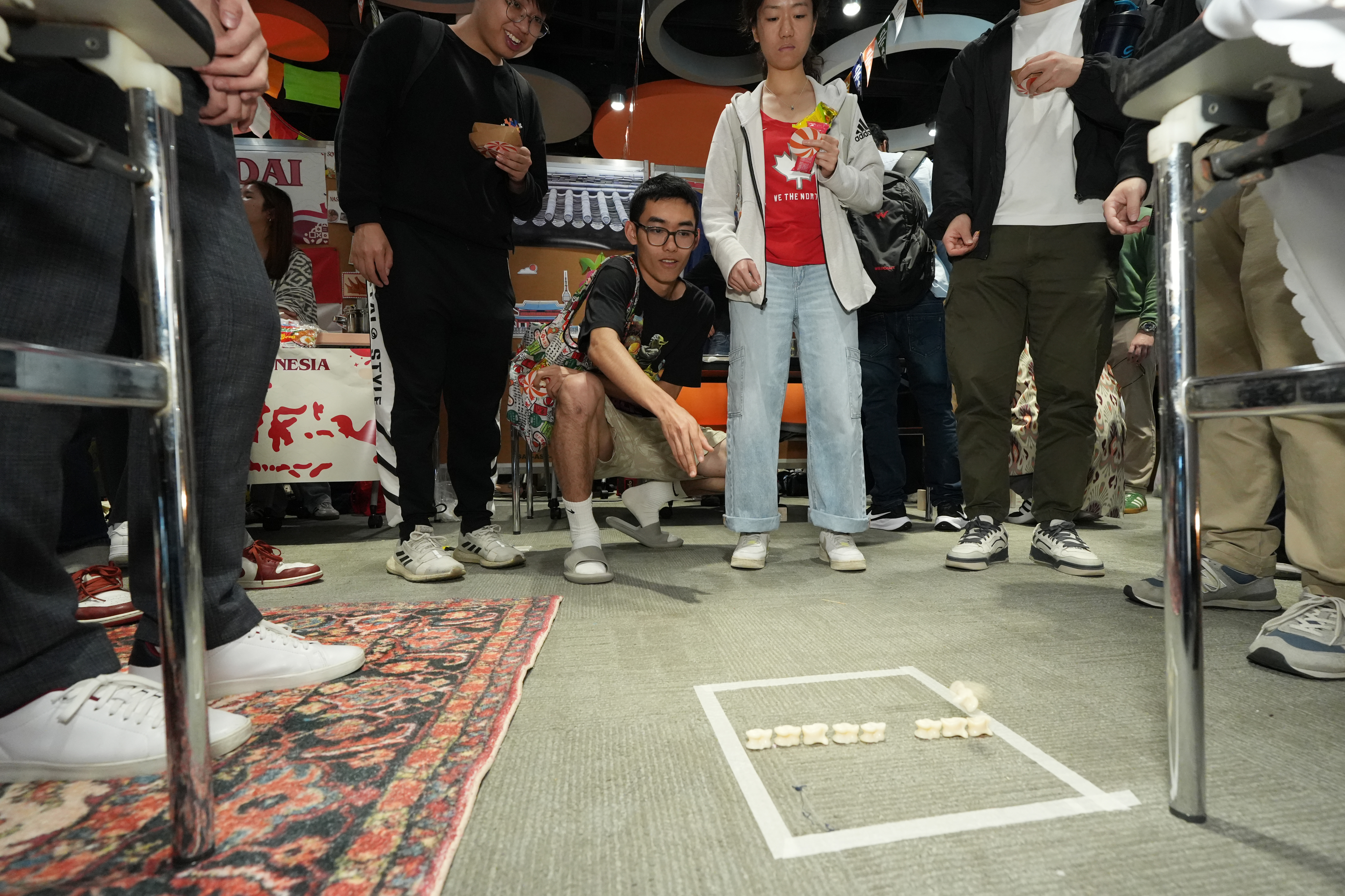 哈萨克斯坦同学介绍当地传统游戏「Assyk」。同学们轮流以弹珠尝试把对方的骰子打出框界以外。