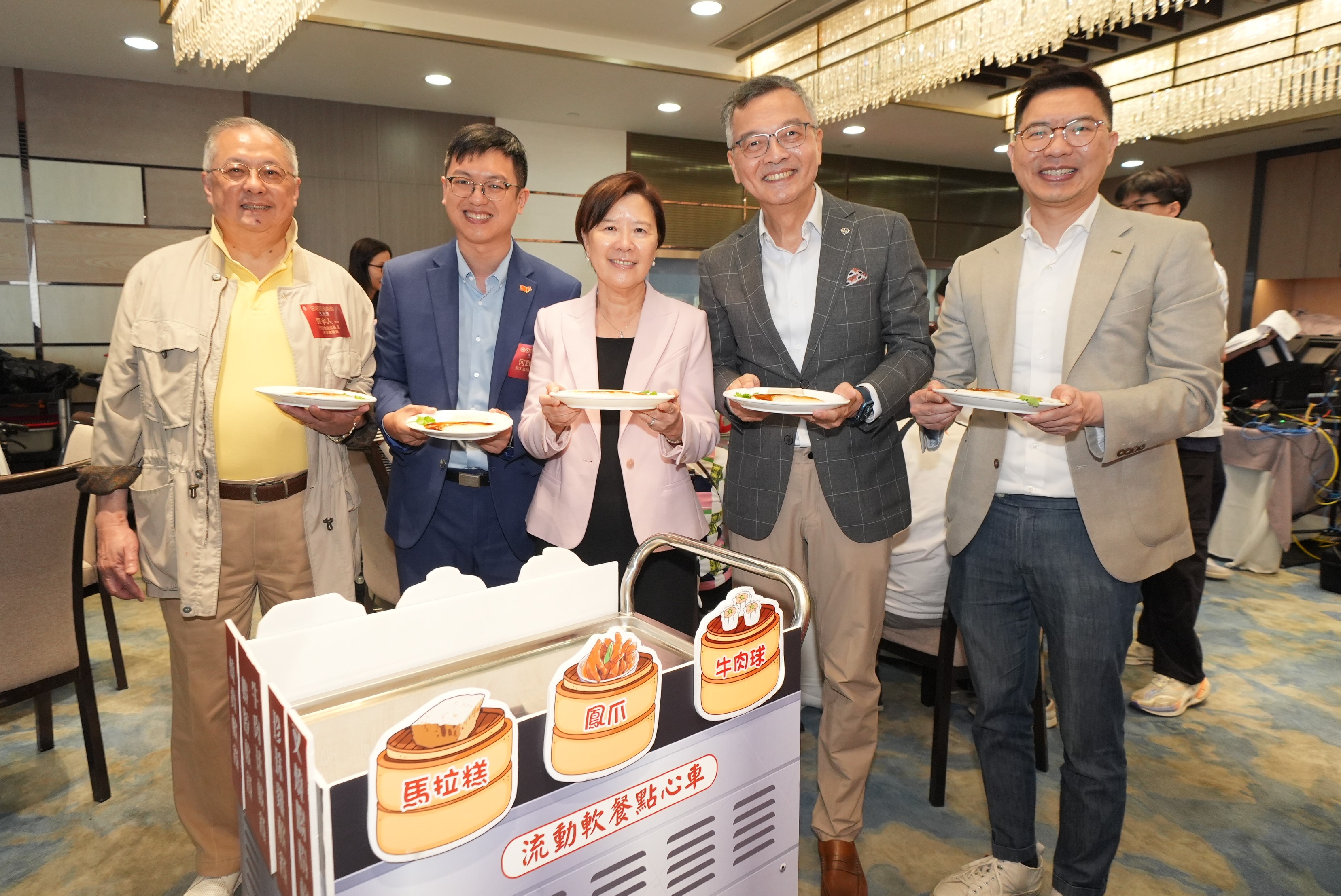 旧式点心车今日重现香港科技大学（科大）校园的中式茶楼内，上面盛载着精致软餐，由行政会议成员暨基督教灵实协会行政总裁林正财医生（右二）、行政会议成员暨立法会议员张宇人先生（左一）、劳工及福利局副局长何启明先生（左二）、黄大仙民政事务专员胡巨华先生（右一）及科大校长叶玉如教授（左三）带领学生和教职员义工队，共同为长者送上叉烧肠粉及萝卜糕。
