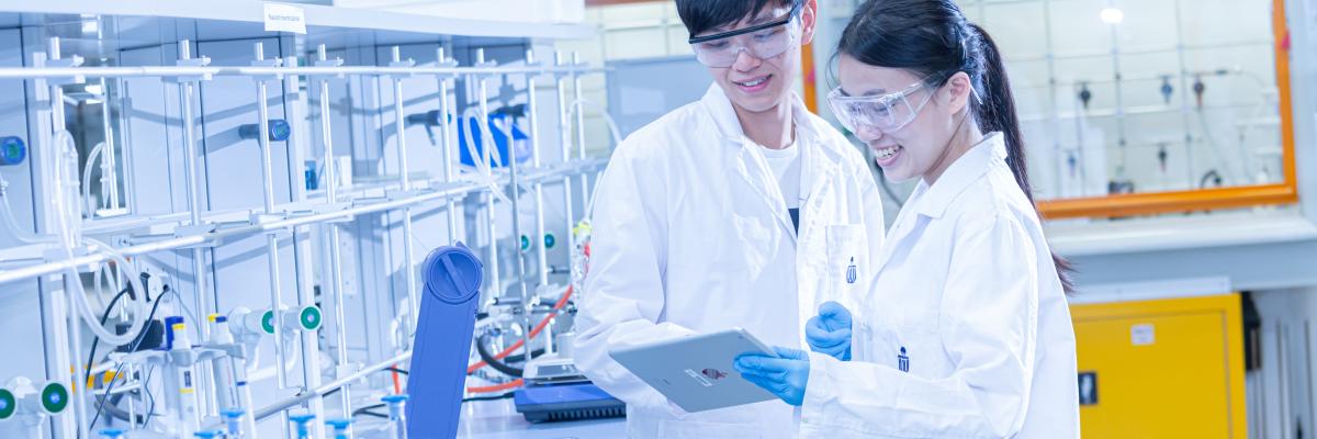 2 people wearing HKUST lab coats inside a science lab